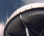 Side of a tower with a water tank on top with various antennas on the side