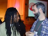 Two people facing each other, one on the left with braided hair, one on the right with a beard