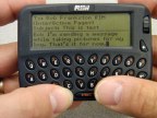 Pager-sized device with tiny keys being pressed by my thumbs