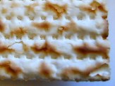 Corner of a piece of matzo, light and dark brown with little holes