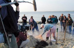 Kevin pulling on canvas surrounded by people and a camera crew with a boom mike