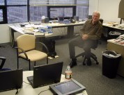 Ray in chair in the midst of a large office with lots of laptops