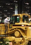 Person climbing up to inspect big yellow machine with treads