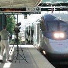 Video camera on tripod and train with dual headlights