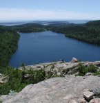 View from cliff down to pond, trees, and then ocean beyond