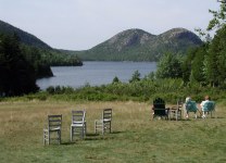 Chairs on lawn facing large pond and two small mountains in the distance