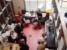 Looking down into a lab with people listening to a student present