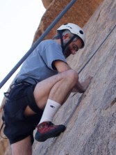 Dan climbing showing ropes, his foot ready to push up, looking at his foot