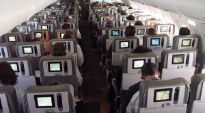 Many seatbacks in a plane each with a screen lit up