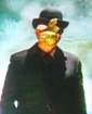 Bob in black suit and black hat with green apple in front of his face in front of clouds and blue sky