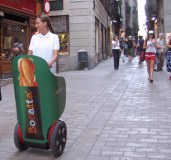Guy on Segway with front covered with sign on coblestones