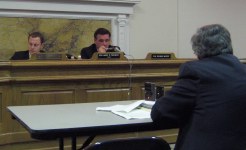 Committee people sitting up front listening to a person testifying from a table facing them